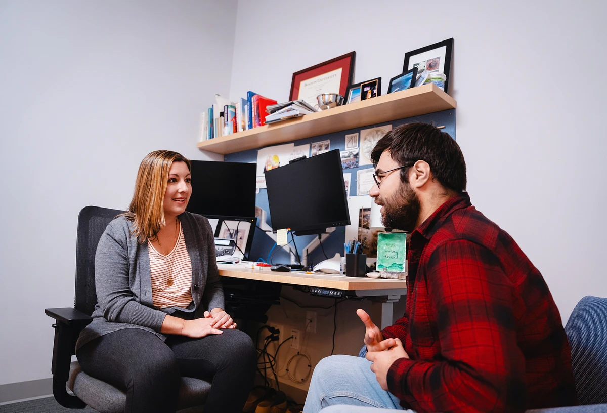 Two people are engaged in a conversation in an office setting.